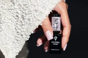 Perłowy manicure w odcieniu 478 Cosmopolitan, dłoń z butelką na tle białych cekinów