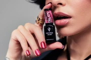 Manicure lakierem Victoria Vynn 479 Cat Eye Velvet Ruby 8 ml, dłoń z butelką i malinowym kocim okiem na paznokciach