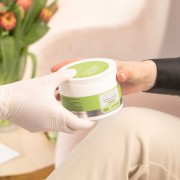 Specjalistka w rękawiczce podaje klientce maść CRACKED HEEL PROTECTOR Pharm Foot