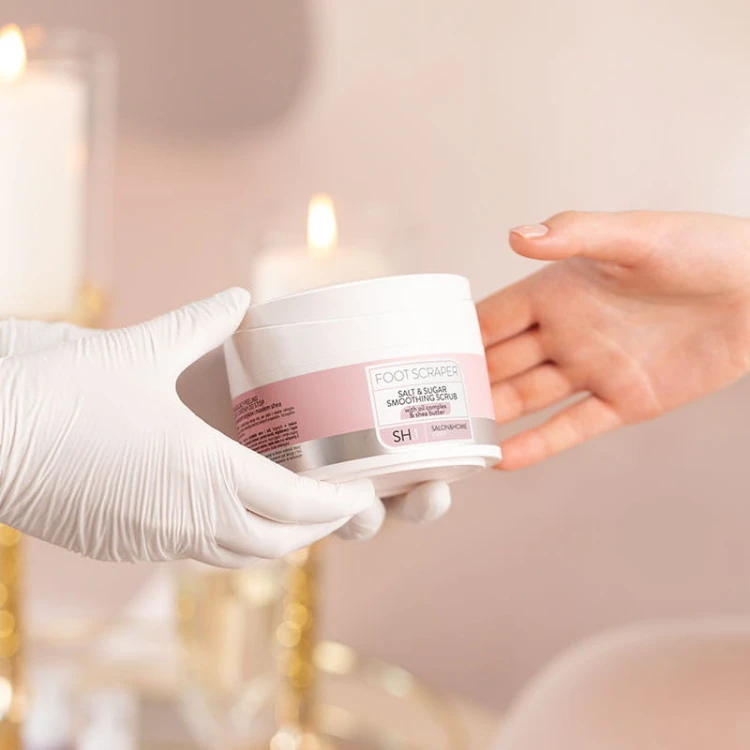 Dłoń w rękawiczce podaje słoik peelingu FOOT SCRAPER Pharm Foot 200 g